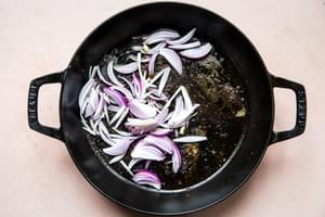 sliced shallots being cooked in a frying pan