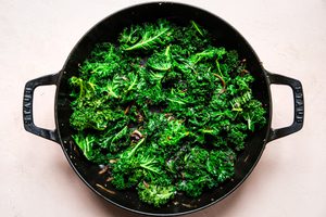cooked shallots and garlic in pan with kale on top
