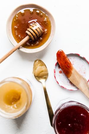 raw honey, local honey on a drizzle stick and strawberry jam