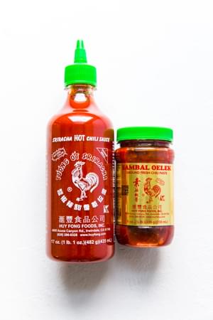 a bottle of sriracha next to a jar of Samba Oelek