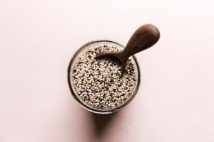 Uncooked quinoa in a jar with a wooden spoon scoop