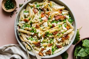 Pasta With Peas Pancetta And Goat Cheese in a bowl with serving spoon