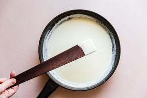 showing finished cream sauce on a wooden spoon