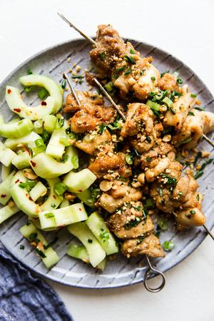 Peanut Sauce Marinated Chicken Skewers on a plate with cucumber salad
