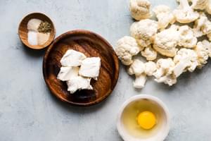ingredients for cauliflower pizza crust, 1 egg, 4 ounces cream cheese and spices in a bowl