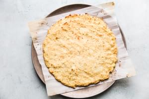 Par cooked cauliflower pizza crust on a parchment on a pizza pan