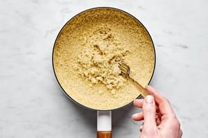 A beautifully cooked pot of perfect couscous, light and fluffy being fluffed with a fork