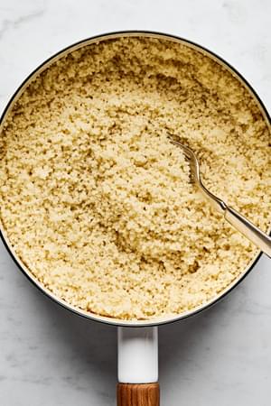A beautifully cooked pot of perfect couscous, light and fluffy being fluffed with a fork
