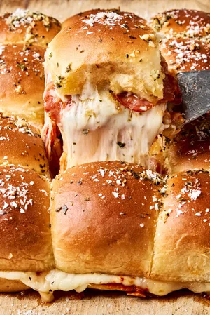 pizza sliders made with cheese and pepperoni with the tops brushed with butter, garlic, oregano and basil
