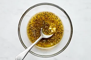 melted butter, garlic, oregano and basil being combined in a glass bowl