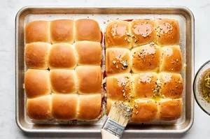 pizza sliders made with Hawaiian rolls being brushed with melted butter and spices