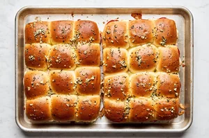 browned pizza sliders topped with melted butter and spices on a baking sheet