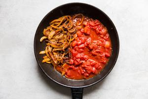 olive oil, onion, garlic diced tomatoes, white wine vinegar and spices cooking in a skillet for salsa bravas