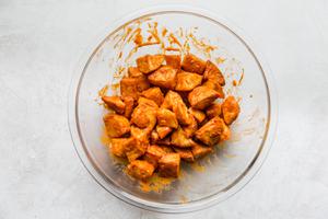 deep fried potatoes being tossed with homemade salsa bravas in a bowl