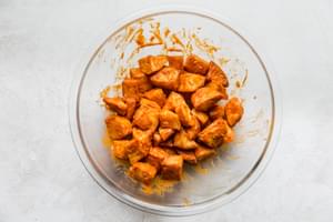 deep fried potatoes being tossed with homemade salsa bravas in a bowl