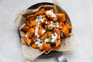 a dish of homemade patatas Bravas topped with garlic aioli and fresh parsley
