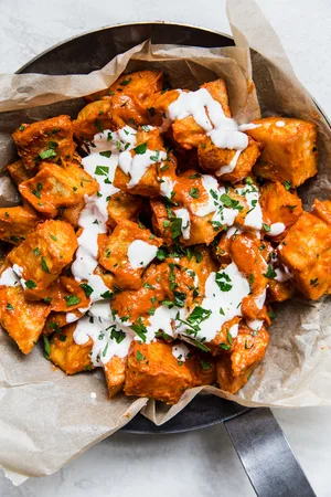 a dish of homemade patatas Bravas topped with garlic aioli and fresh parsley