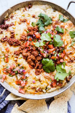 Queso Fundido Dip in a serving dish with chorizo , cilantro and pico de gallo