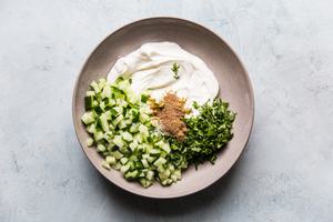 yogurt, spices, cucumbers and coriander in a ceramic bowl for raita