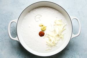 coconut milk, onions and curry in a white skillet