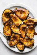 Roasted acorn squash halves seasoned with butter, brown sugar, salt, chili powder, and cumin, baked to golden perfection.