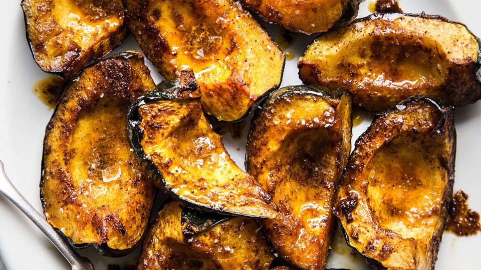 Roasted acorn squash halves seasoned with butter, brown sugar, salt, chili powder, and cumin, baked to golden perfection.