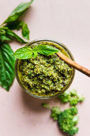 glass jar of roasted broccoli pesto topped with fresh basil