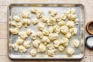 cauliflower tossed with olive oil and seasoned with salt and pepper on a baking sheet