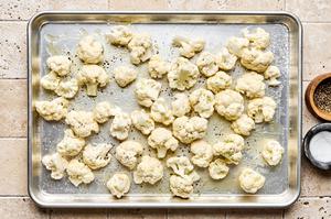 cauliflower tossed with olive oil and seasoned with salt and pepper on a baking sheet
