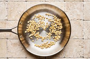 pine nuts being toasted in a small skillet