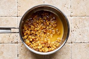 golden raisins, chicken stock, and white wine vinegar simmering in a sauce pan