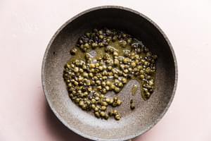 capers frying in olive oil in a skillet