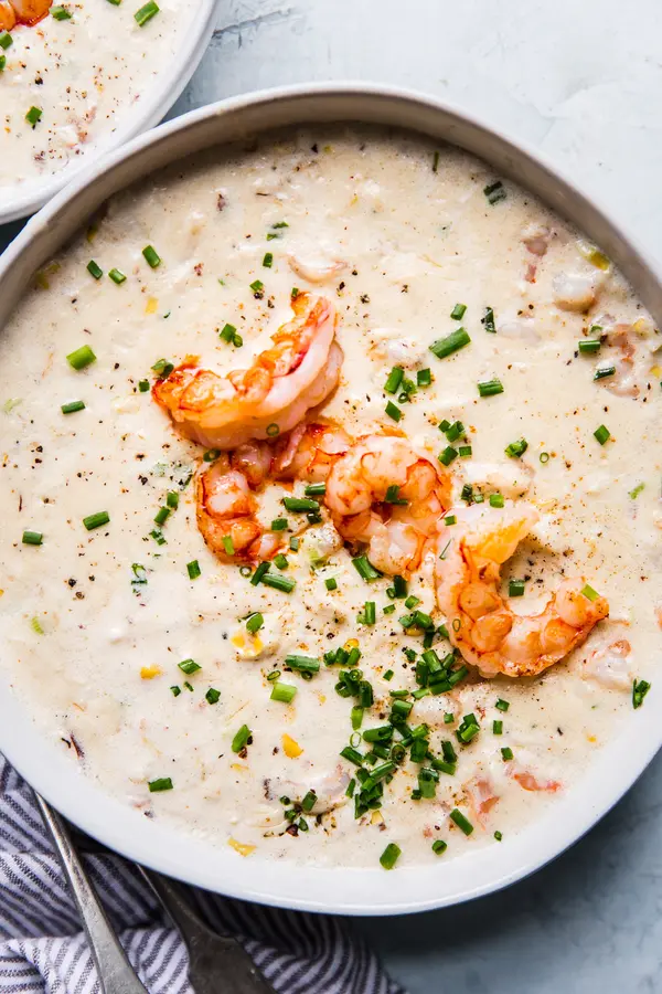 seafood bisque topped with fresh shrimp and chives in a white bowl