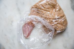 raw chicken in a plastic bag being coated with breadcrumbs and spices to make homemade shake and bake chicken