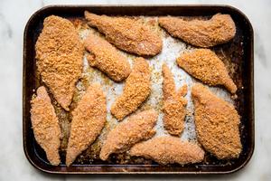 homemade shake and bake chicken arranged on a baking sheet on the counter ready to go into the oven