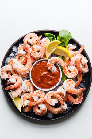 shrimp cocktail sauce with shrimp over ice on a black plate