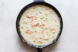 butter, carrots, onion and celery sautéed in a cast iron skillet with chicken stock and milk added