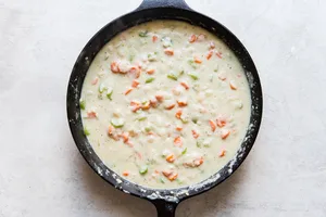 butter, carrots, onion and celery sautéed in a cast iron skillet with chicken stock and milk added