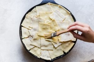 puff pastry topped chicken pot pie being brushed with and egg wash