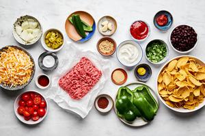 bell peppers, onion, ground beef, jalapeño, ketchup, tomato paste, spices, fritos and black beans in prep bowls