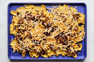 fritos topped with sloppy joe ground beef and shredded cheese on a baking sheet
