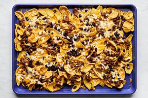 fritos topped with sloppy joe ground beef and melted shredded cheese on a baking sheet