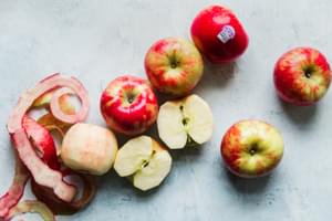 red honey crips apples on a blue surface. Some peeled and cut in half.