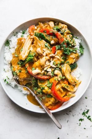slow cook pumpkin chicken curry in a bowl over white rice and topped with fresh cilantro and toasted cashews