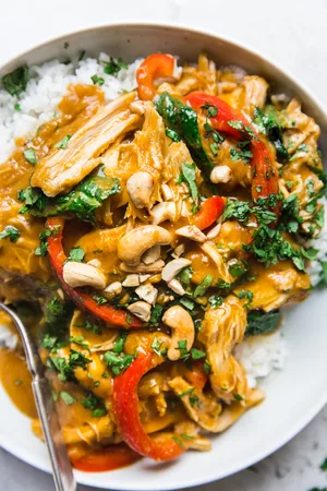 bowl of pumpkin curry over rice with fresh cilantro and crushed cashews
