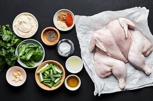 brown sugar, paprika, garlic powder, pepper, salt, olive oil, a whole chicken, fresh herbs garlic, mayo and lemons in bowls