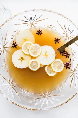 punch bowl filled with spiced bourbon punch, sliced apples, sliced lemons and star anise.