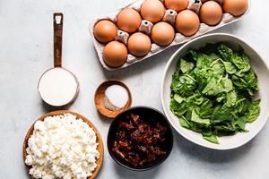 ingredients laid out, eggs, milk, salt, pepper, sun dried tomatoes, feta and spinach for homemade egg cups