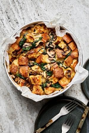 spinach mushroom strata made with eggs, cream, onion, spices and dijon in a parchment lined baking pan