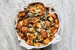 spinach mushroom strata made with eggs, cream, onion, spices and dijon in a parchment lined baking pan